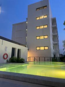 a building with a swimming pool in front of it at Pinotel Prachuap - โรงแรมพิโนเทล ประจวบ in Prachuap Khiri Khan