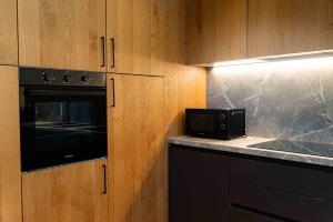 a kitchen with wooden cabinets and a black microwave at Casa vacanza Garcia in Paluzza