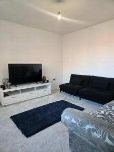 a living room with a couch and a flat screen tv at Glams luxury home in Wolverhampton