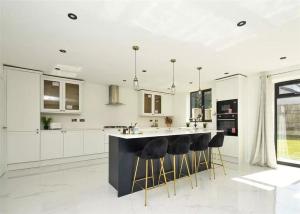 a kitchen with white cabinets and a black island with stools at Glams luxury home in Wolverhampton