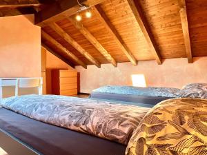 two beds in a room with wooden ceilings at Casa Bùri in Trarego