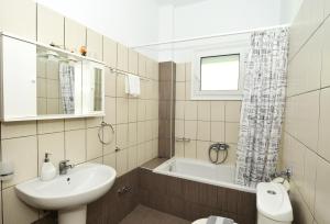 a bathroom with a sink and a tub and a toilet at Studios Avra in Skala Rachoniou