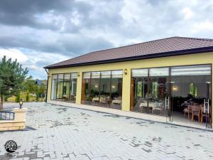 a yellow building with glass windows and a patio at River Hotel Restaurant in Quba