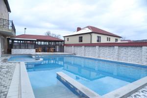a swimming pool with blue water in front of a house at Qusar Shahdag Garden Hotel in Qusar