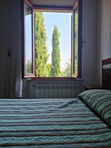 a bedroom with a bed and a large window at Affittacamere Dal Falco in Pienza +7 photos