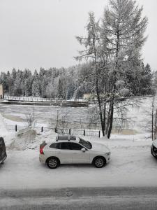 a white car parked on the side of a snow covered road at Brahenkatu Apartment in Kajaani +6 photos
