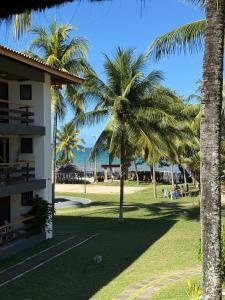 a resort with palm trees next to a building at Flat Ilhéus Olivença pé na areia no Condomínio Jubiaba in Ilhéus