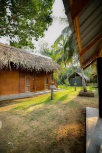 a house with a straw roof and a yard at Jungle View River Camping in Udawalawe