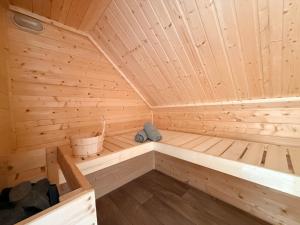 a wooden sauna with a bench and a bucket at Pure Wellness Bungalows 52 Sauna&Hottub in Ewijk