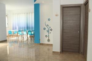 a dining room with a door and a table with blue chairs at Luca's House - Villa sul mare con piscina in Giovinazzo