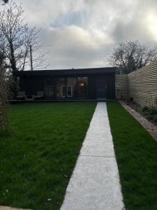 a house with a walkway in front of a yard at The Cabin in St. Ives