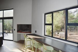 a dining room with a table and chairs and windows at Mukaya Haven in Marloth Park