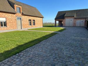 a brick house with a driveway next to a building at 't Caeneghems Goed in Tielt
