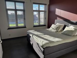 a bedroom with a large bed with two windows at 't Caeneghems Goed in Tielt