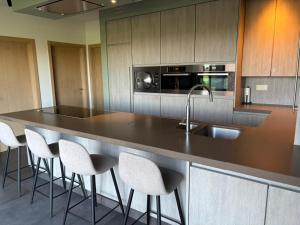 a kitchen with a counter with a sink and stools at 't Caeneghems Goed in Tielt +4 photos