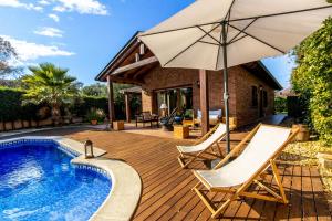 a deck with an umbrella and chairs next to a pool at Catalunya Casas A Costa Brava gem - only a few minutes to the beach! in Vidreres