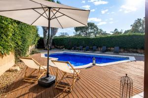 a patio with two chairs and an umbrella next to a swimming pool at Catalunya Casas A Costa Brava gem - only a few minutes to the beach! in Vidreres