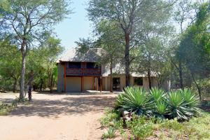 a building in the middle of a forest with trees at Mukaya Haven in Marloth Park