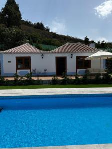 a house with a blue swimming pool in front of it at Villas Morera in Breña Baja