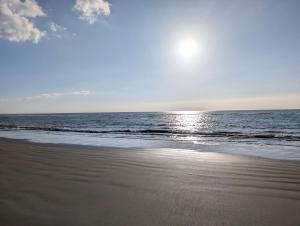 a beach with the sun rising over the ocean at Cartref Guesthouse - Room 2 Ensuite in Aberdyfi