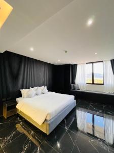 a bedroom with a large white bed with black walls at Stylish Condo Near Nai Harn Beach Full Facilities Utopia M720 in Rawai Beach