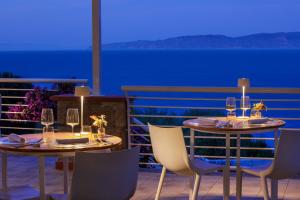 two tables and chairs with wine glasses on a balcony at Hotel L'Arenella in Giglio Porto