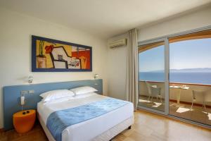 a bedroom with a bed and a view of the ocean at Hotel L'Arenella in Giglio Porto