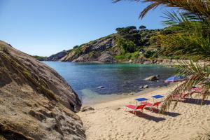 a beach with chairs and umbrellas on the sand at Hotel L'Arenella in Giglio Porto