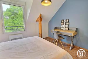a bedroom with a bed and a desk and a window at La maison de chris in Theix