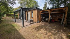 a small cabin with a black roof at Rustige natuur lodge bij Deventer met privé terras in Gorssel