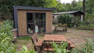 a small cabin with a picnic table in a garden at Rustige natuur lodge bij Deventer met privé terras in Gorssel