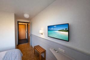 a bedroom with a flat screen tv on the wall at Hôtel La Croisée Neuchâtel in Malvilliers
