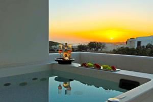 a bathroom with a tub with a sunset in the background at Adama Mykonos Boutique Hotel in Mikonos