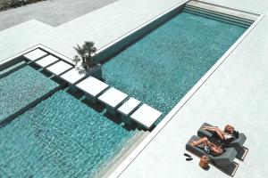 an overhead view of a swimming pool with a person sitting in a chair next to at Adama Mykonos Boutique Hotel in Mikonos