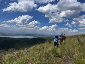 a group of people walking on a grassy hill at Kings Home Stay in Nakuru