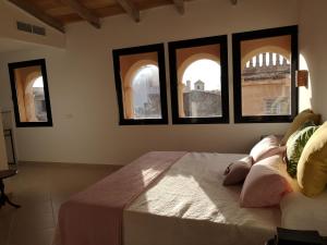 a bedroom with three windows and a bed with pillows at s'Herència in Porreres +8 photos