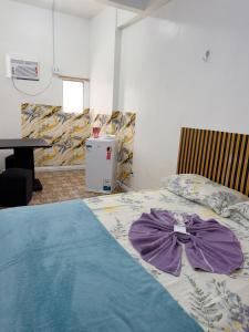 a bedroom with a bed with a purple bow on it at Quarto no centro in Manaus +7 photos