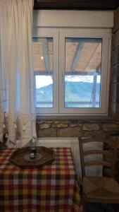 a room with a table and two windows at Villa Lochia - Το Πέτρινο του Θωμά in Rámia
