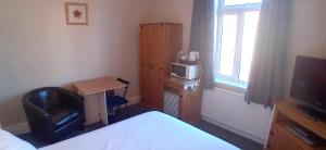 a bedroom with a bed and a desk and a television at Home and Away near the Spa in Bridlington