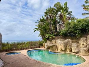 a swimming pool with a rock wall next to the ocean at Aura Mar in Ponta do Ouro