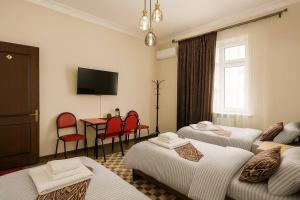 a hotel room with four beds and a table and chairs at SAM GREEN HOUSE Hostel in Samarkand