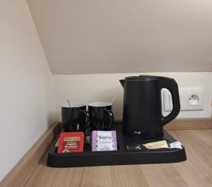 a black coffee pot on a tray with books at Le Grand Hôtel Ussel ''nouvelle Gérance 2023'' in Ussel