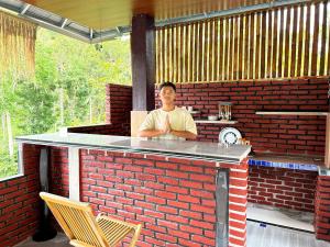 a man sitting at a bar in a brick wall at Goa Walet Cottage in Praya