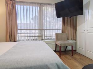a bedroom with a bed and a chair and a window at Apart Hotel Cambiaso in Santiago