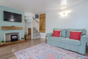 a living room with a blue couch and a fireplace at Crossways Cottage, Dog-Friendly Cottage Near the Beach in Winterton-on-Sea
