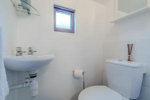 a white bathroom with a toilet and a sink at Crossways Cottage, Dog-Friendly Cottage Near the Beach in Winterton-on-Sea +11 photos