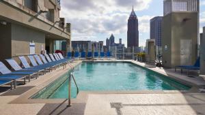 a swimming pool on top of a building with chairs at Luxurious Midtown Apartment w Sky Lounge & Pool in Atlanta
