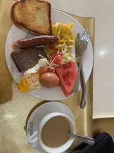a plate of breakfast food with a sandwich and a cup of coffee at Mable Home in Mzuzu