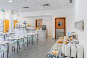 a restaurant with tables and chairs and a kitchen at HI Lousã – Pousada de Juventude in Lousã