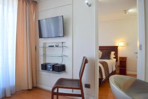 a bathroom with a bed and a television on a wall at Apart Hotel Cambiaso in Santiago